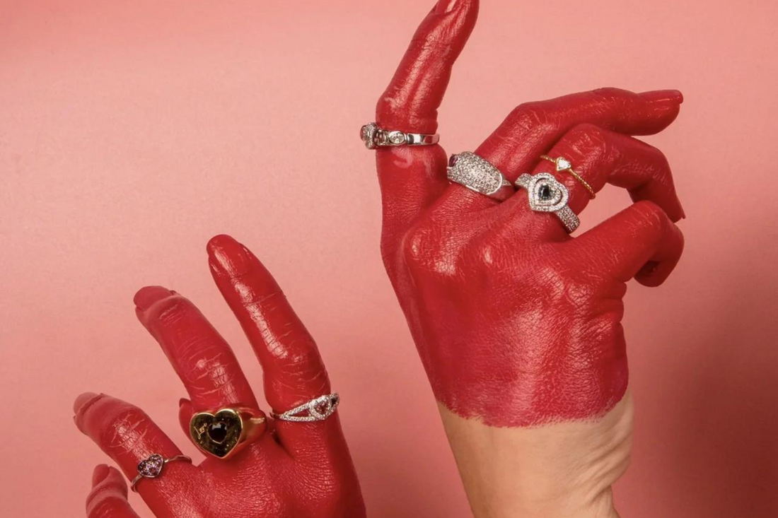 Hand with red paint wearing multiple jewelry