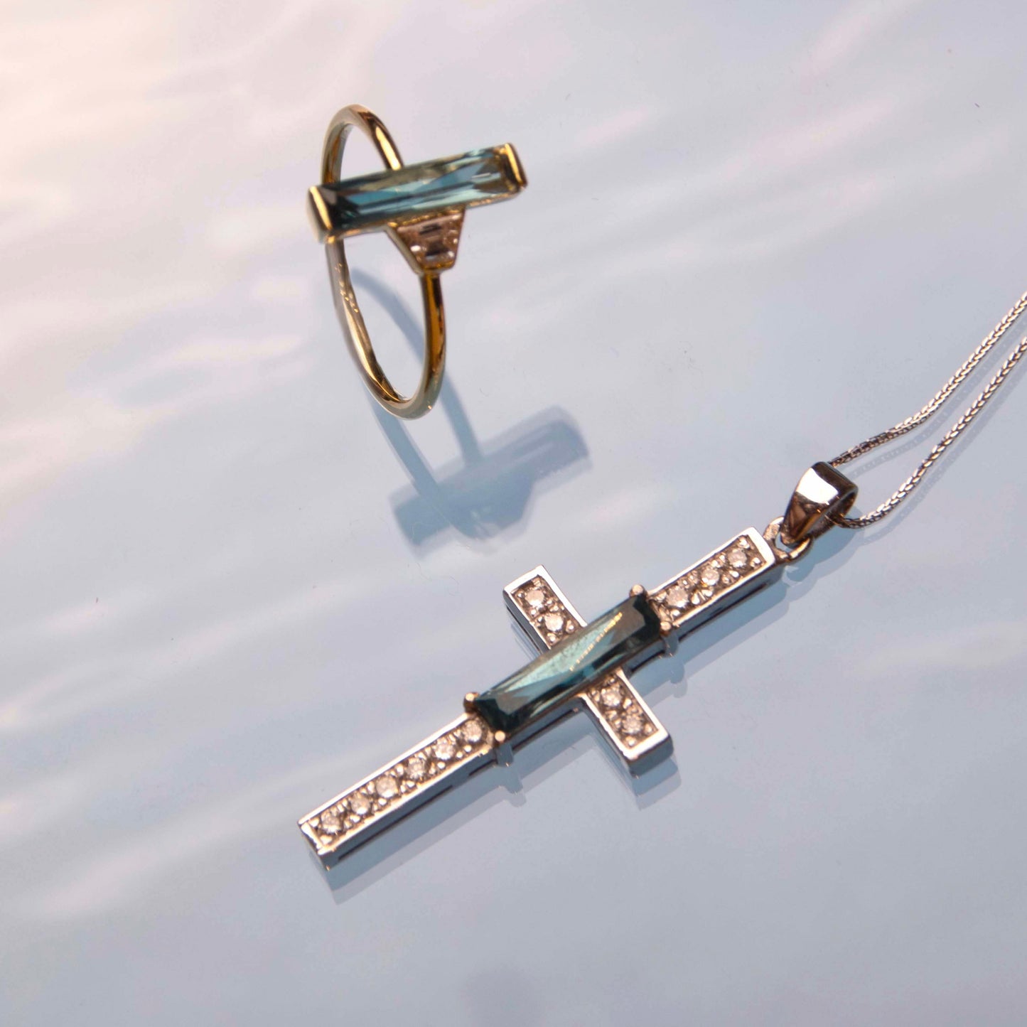 14-karat white gold cross pendant is a stunning piece of jewelry that features a scissor-cut aquamarine as its centerpiece, accented with sparkling diamonds.