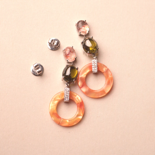 These sterling silver earrings are a unique and eye-catching combination of colors and textures, featuring a sunstone cabochon, peridot cabochon, and orange acrylic hoops.