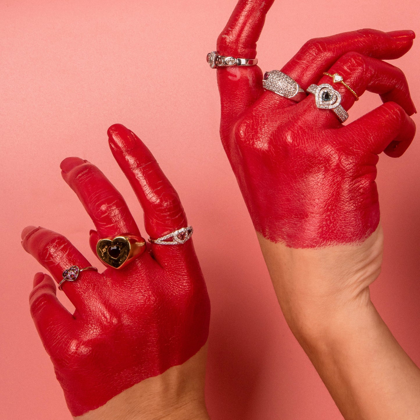 Hand with red paint wearing multiple rings